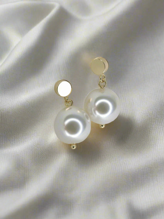 Pearl earrings with gold accents on a light gray background